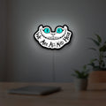 Alice in Wonderland Cheshire Cat LED lightbox hanging on a room wall with soft white light