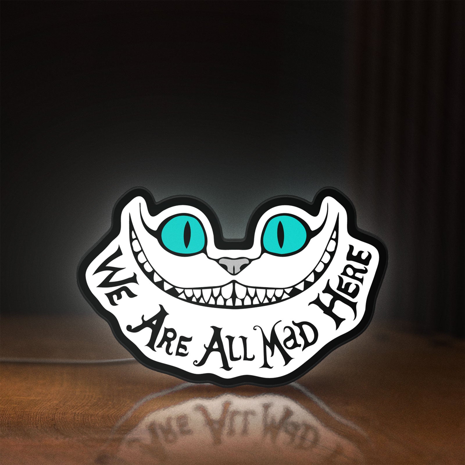 Front view of Alice in Wonderland Cheshire Cat LED lightbox sign glowing on a wooden desk