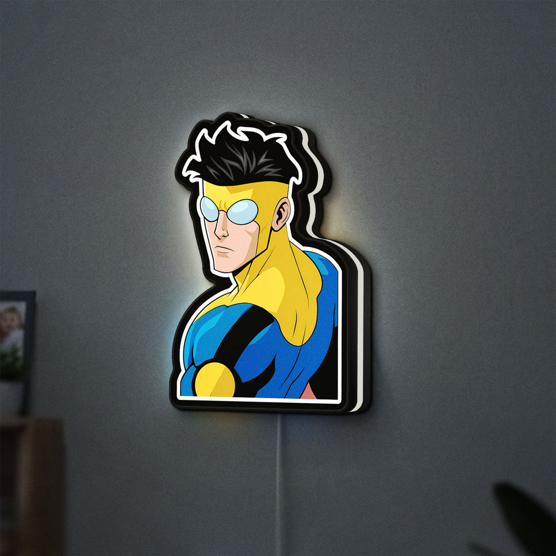 Invincible Title Logo Superhero LED lightbox hanging on a wall with white glow