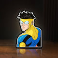 Front view of Invincible Title Logo Superhero LED lightbox sign glowing on a wooden desk
