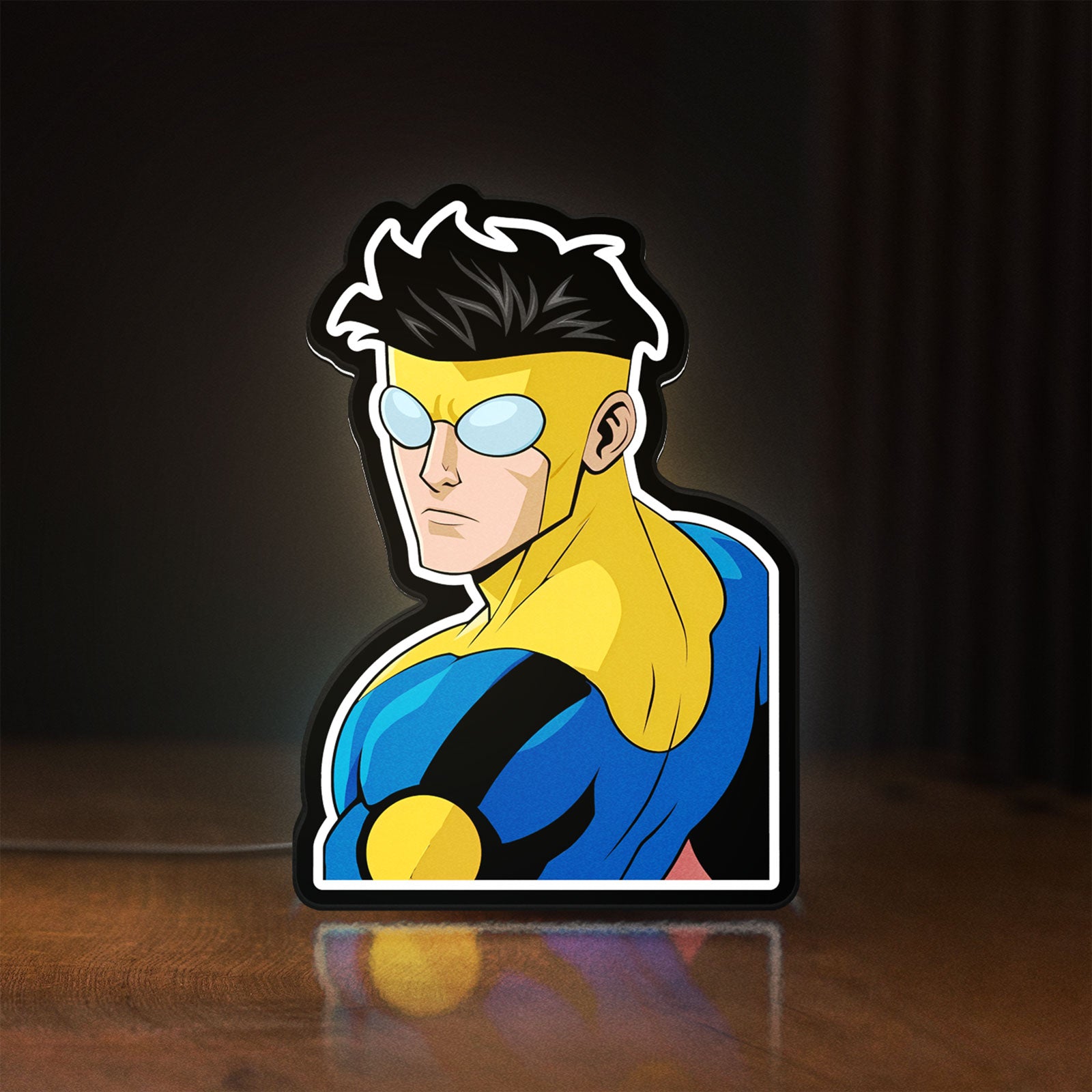 Front view of Invincible Title Logo Superhero LED lightbox sign glowing on a wooden desk