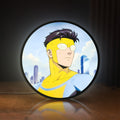 Front view of Invincible Title Logo Superhero LED lightbox sign glowing on a wooden desk
