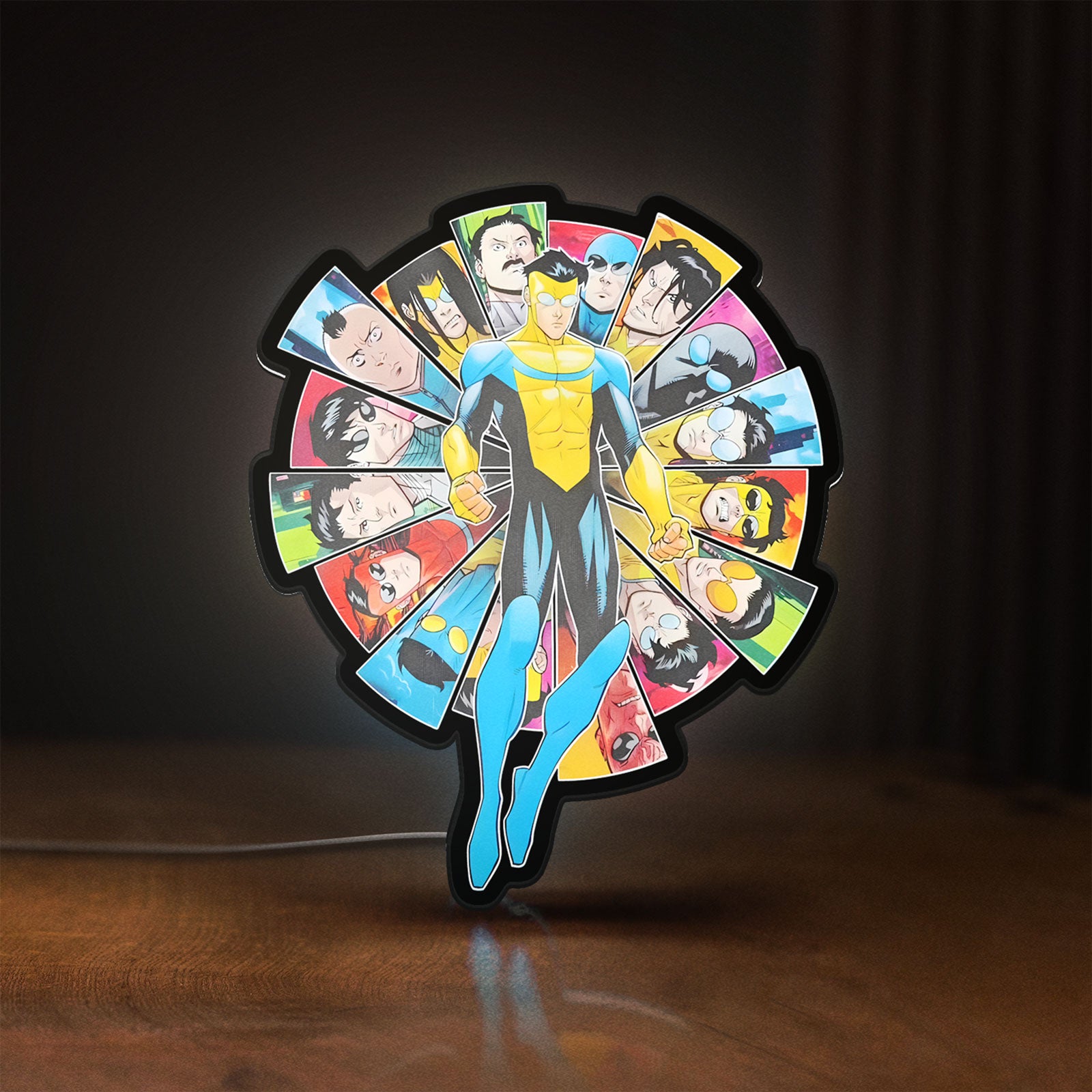 Front view of Invincible Title Logo Superhero LED lightbox sign glowing on a wooden desk