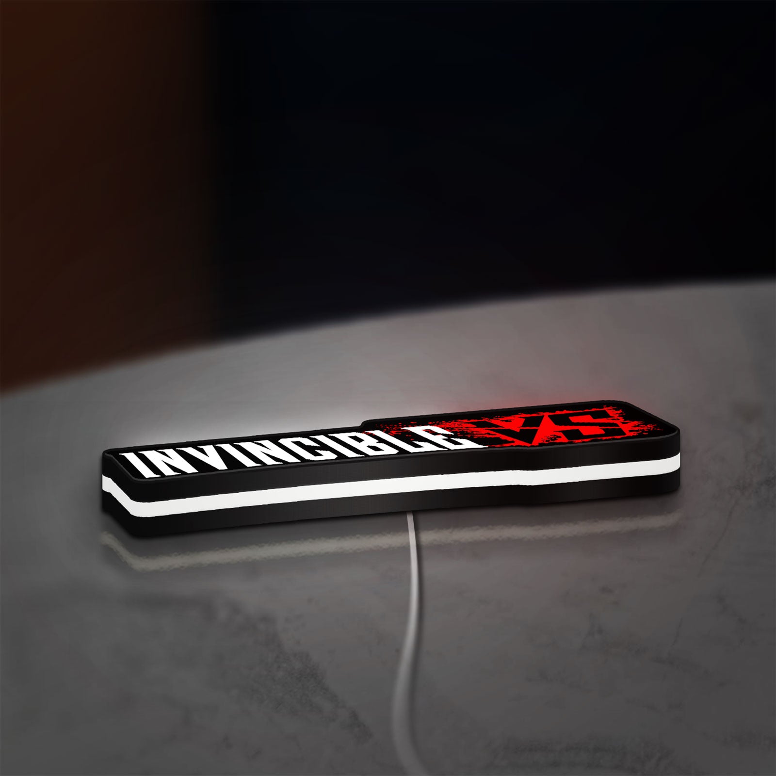Invincible V Logo Mark Grayson LED lightbox lying flat on a desk with white glow