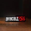 Front view of Invincible V Logo Mark Grayson LED lightbox sign glowing on a wooden desk