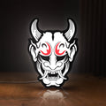 Front view of Cyberpunk Japanese Oni Mask Demon LED lightbox sign glowing on a wooden desk