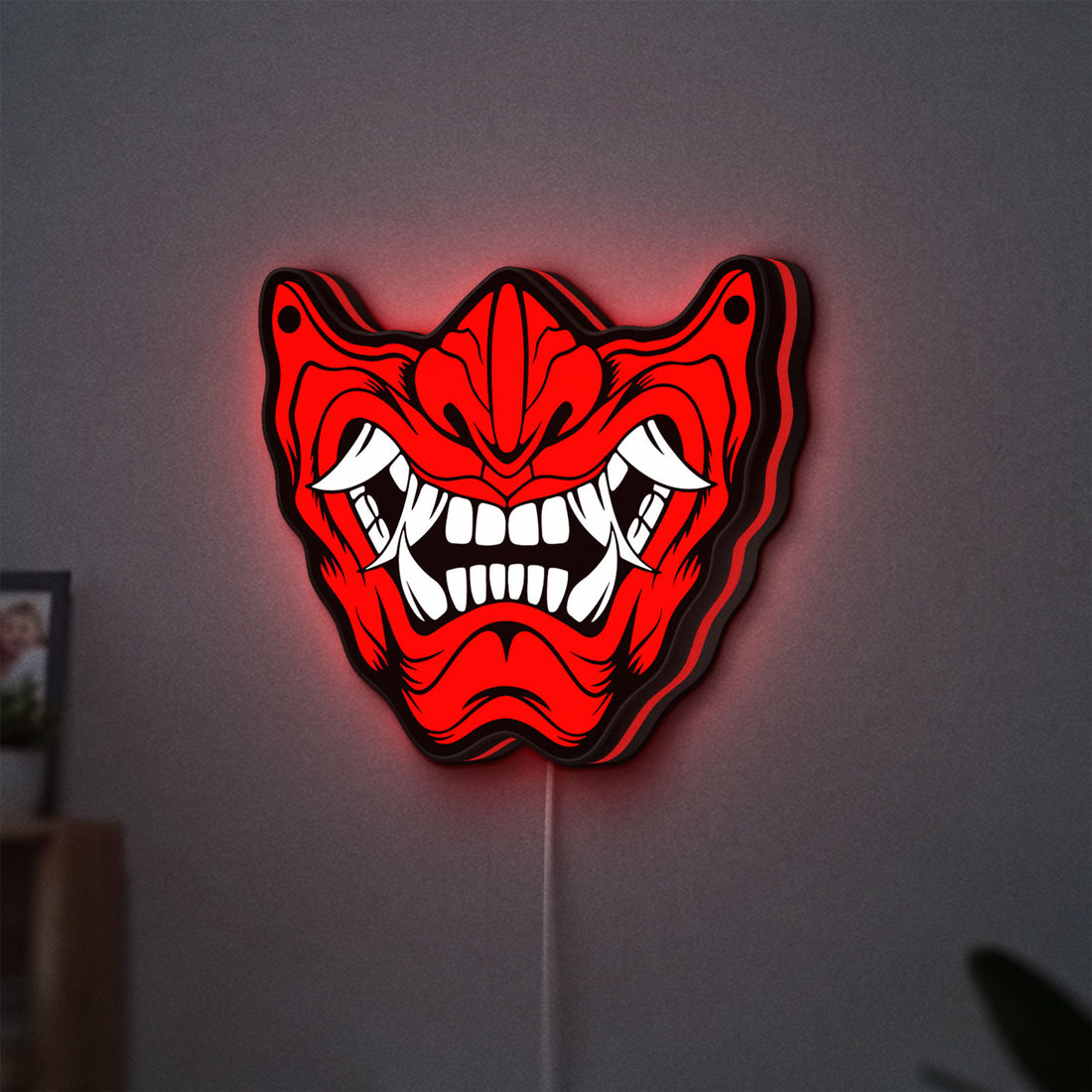 Oni Mas LED lightbox hanging on a wall with red glow