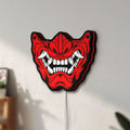 Unlit Oni Mas LED lightbox mounted on a wall in daylight