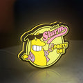 Futurama Slurm Cola Sci-Fi Comedy LED lightbox standing on a desk from an angled side view with yellow glow