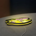 Futurama Slurm Cola Sci-Fi Comedy LED lightbox lying flat on a desk with yellow glow