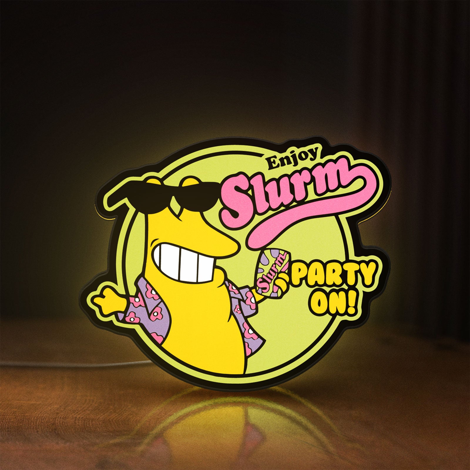 Front view of Futurama Slurm Cola Sci-Fi Comedy LED lightbox sign glowing on a wooden desk