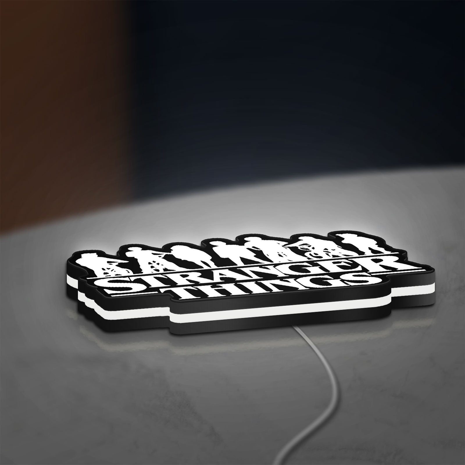Stranger Things Logo The Upside Down LED lightbox lying flat on a desk with white glow
