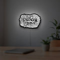 Stranger Things Logo The Upside Down LED lightbox hanging on a room wall with soft white light