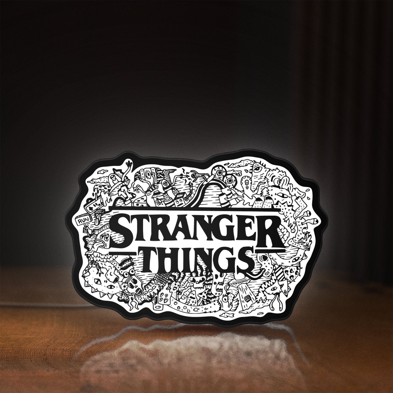 Front view of Stranger Things Logo The Upside Down LED lightbox sign glowing on a wooden desk