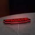 Stranger Things Logo The Upside Down LED lightbox lying flat on a desk with red glow