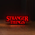 Front view of Stranger Things Logo The Upside Down LED lightbox sign glowing on a wooden desk