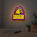 This is an Outrage Meme Funny Quote LED lightbox hanging on a room wall with soft pink light