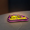 This is an Outrage Meme Funny Quote LED lightbox lying flat on a desk with pink glow