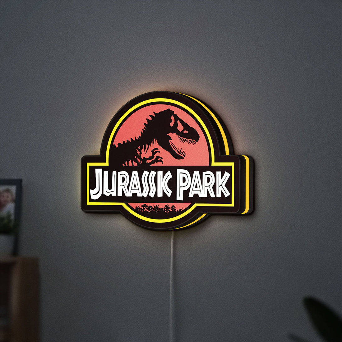 Jurassic Park LED lightbox hanging on a wall with yellow glow