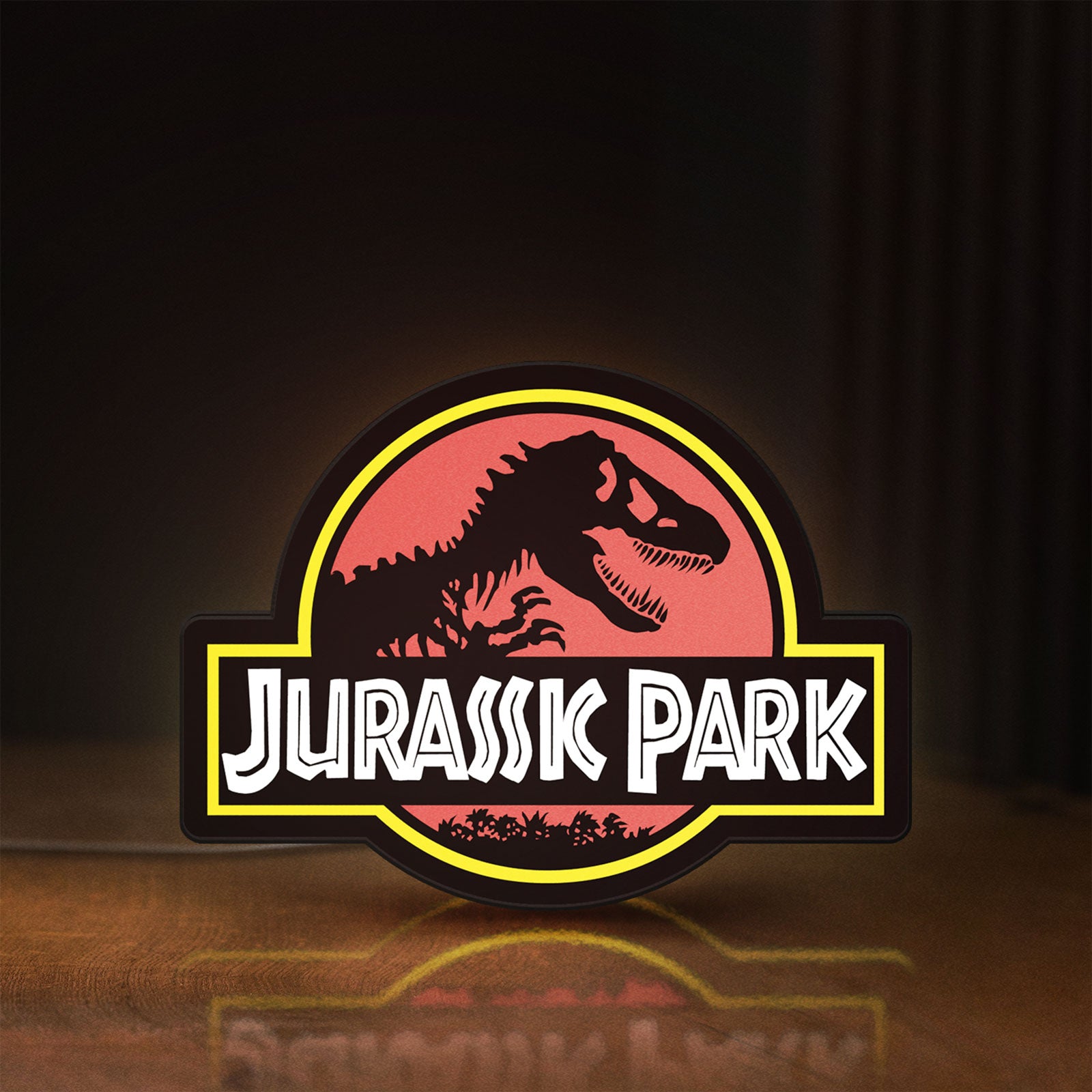 Front view of Jurassic Park LED lightbox sign glowing on a wooden desk