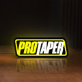 Front view of Pro Taper LED lightbox sign glowing on a wooden desk