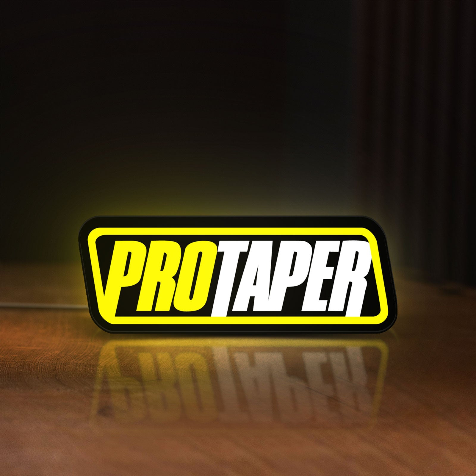 Front view of Pro Taper LED lightbox sign glowing on a wooden desk