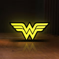 Front view of WONDER WOMAN LED lightbox sign glowing on a wooden desk