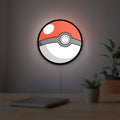 Pokeball LED lightbox hanging on a room wall with soft white light