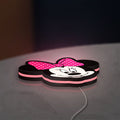 Minnie Mouse Head LED lightbox lying flat on a desk with pink glow
