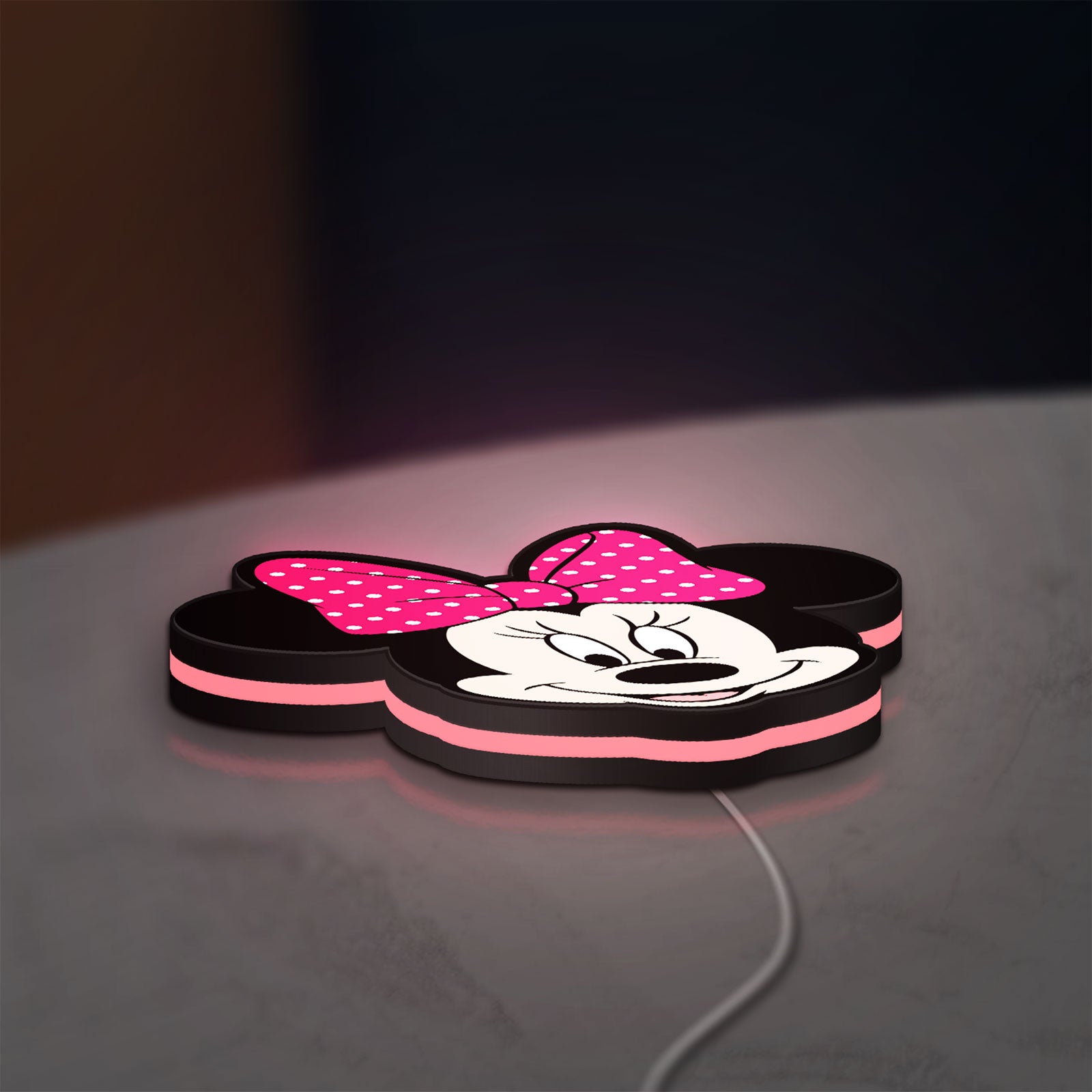 Minnie Mouse Head LED lightbox lying flat on a desk with pink glow