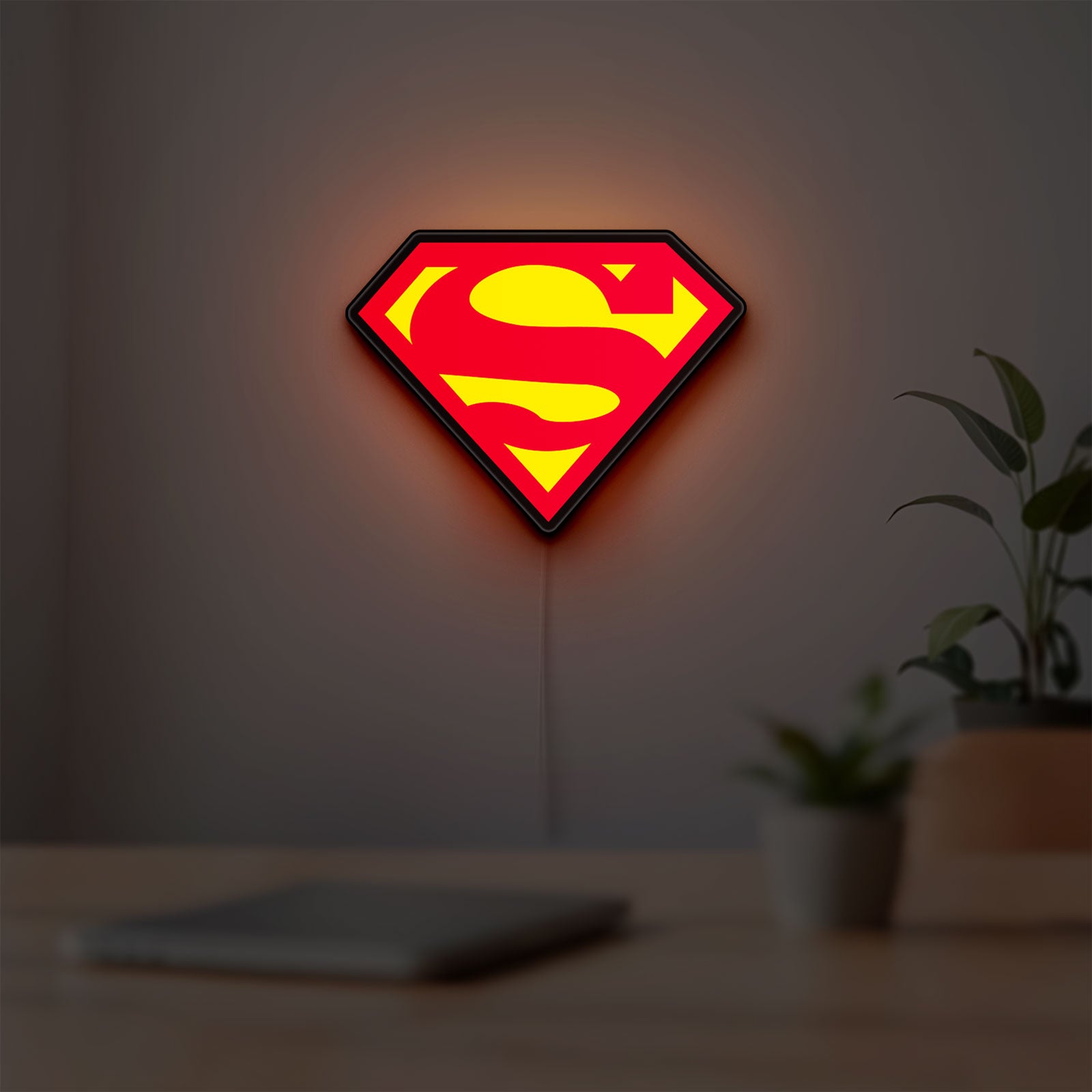Superman S LED lightbox hanging on a room wall with soft red light