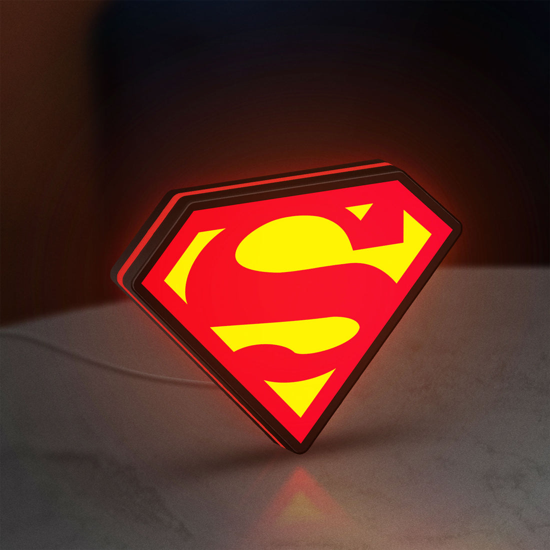 Superman S LED lightbox hanging on a wall with red glow