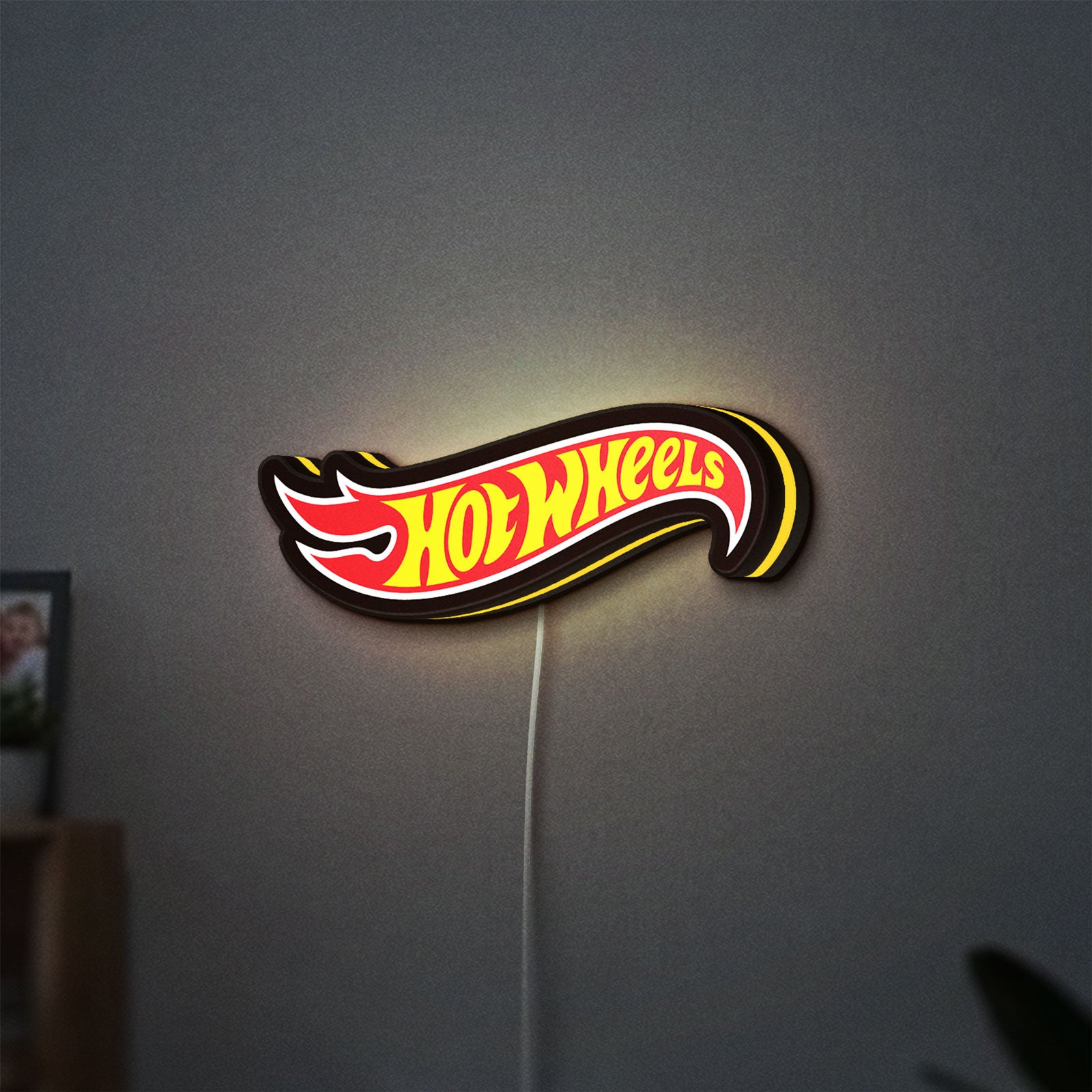Hot Wheels Sign LED lightbox hanging on a wall with yellow glow