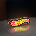 Hot Wheels Sign LED lightbox standing on a desk from an angled side view with yellow glow