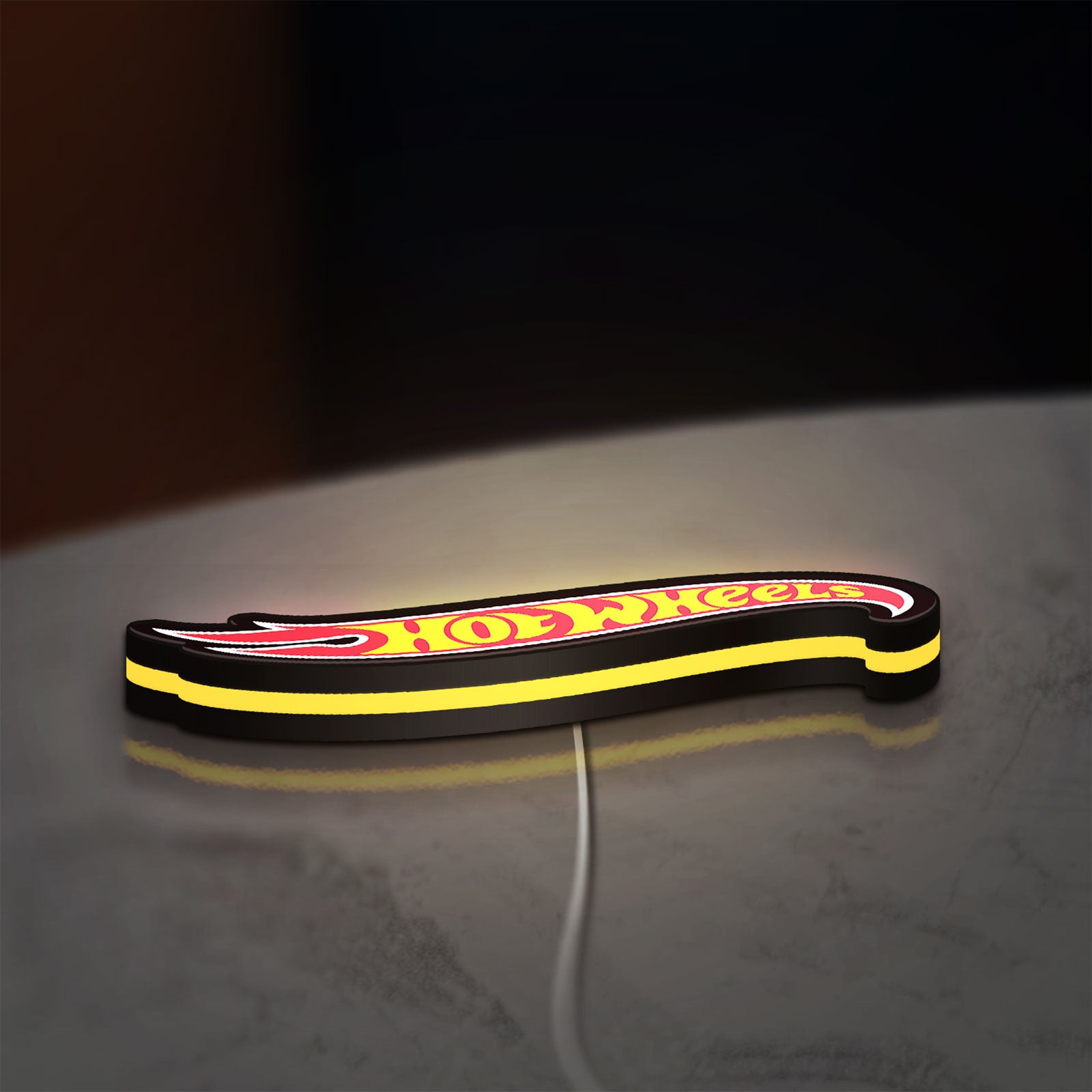 Hot Wheels Sign LED lightbox lying flat on a desk with yellow glow