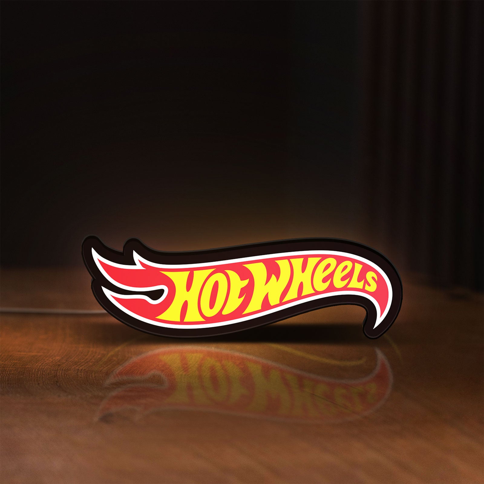 Front view of Hot Wheels Sign LED lightbox sign glowing on a wooden desk