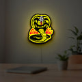 Cobra Kai LED lightbox hanging on a room wall with soft yellow light