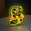Cobra Kai LED lightbox standing on a desk from an angled side view with yellow glow