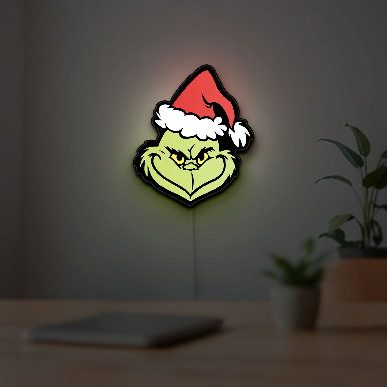 Grinch LED lightbox hanging on a room wall with soft green light