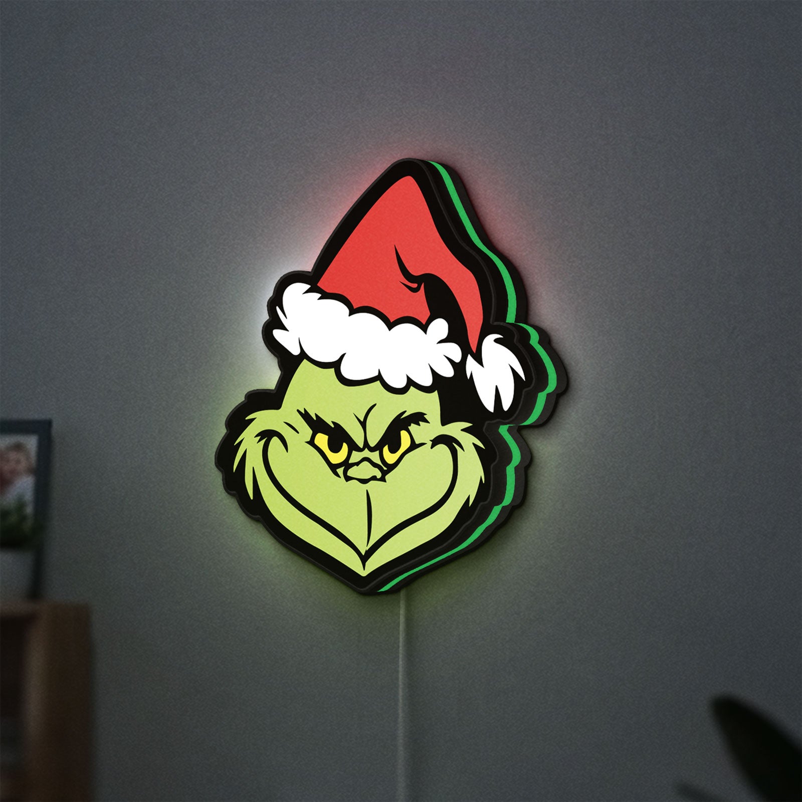 Grinch LED lightbox hanging on a wall with green glow