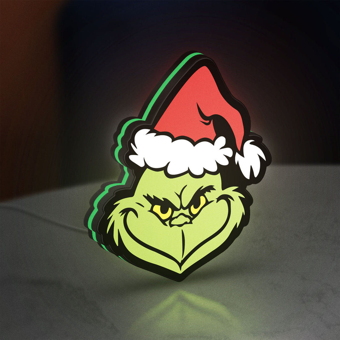 Grinch LED lightbox hanging on a wall with green glow