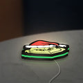 Grinch LED lightbox lying flat on a desk with green glow