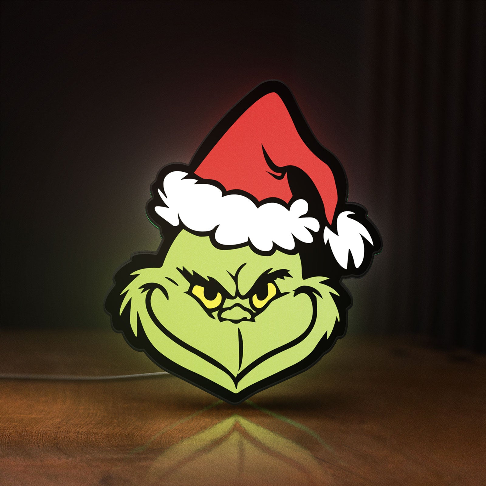 Front view of Grinch LED lightbox sign glowing on a wooden desk