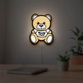 Oso Moschino Toy LED lightbox hanging on a room wall with soft white light