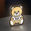 Oso Moschino Toy LED lightbox standing on a desk from an angled side view with white glow