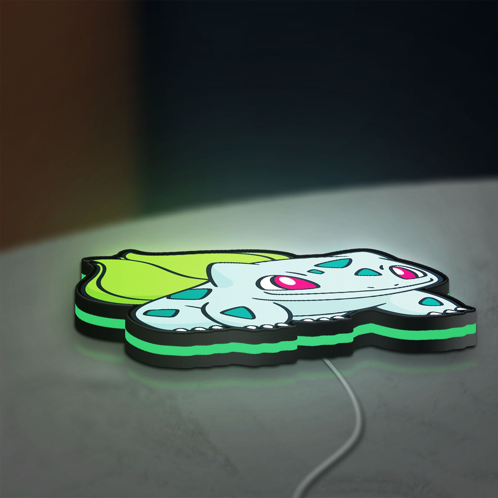 Bulbasaur LED lightbox lying flat on a desk with green glow