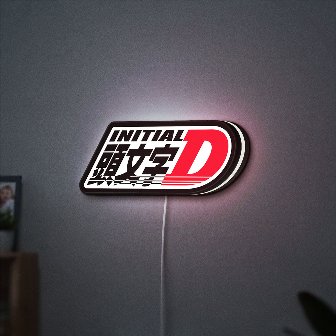 Initial D LED lightbox hanging on a wall with white glow