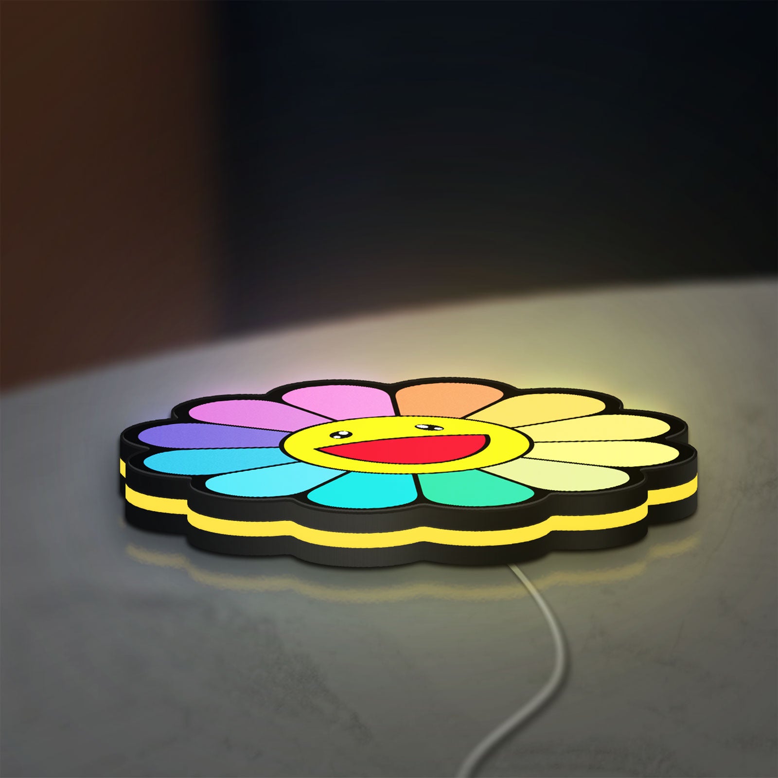Takashi Murakami Rainbow Flower LED lightbox lying flat on a desk with yellow glow
