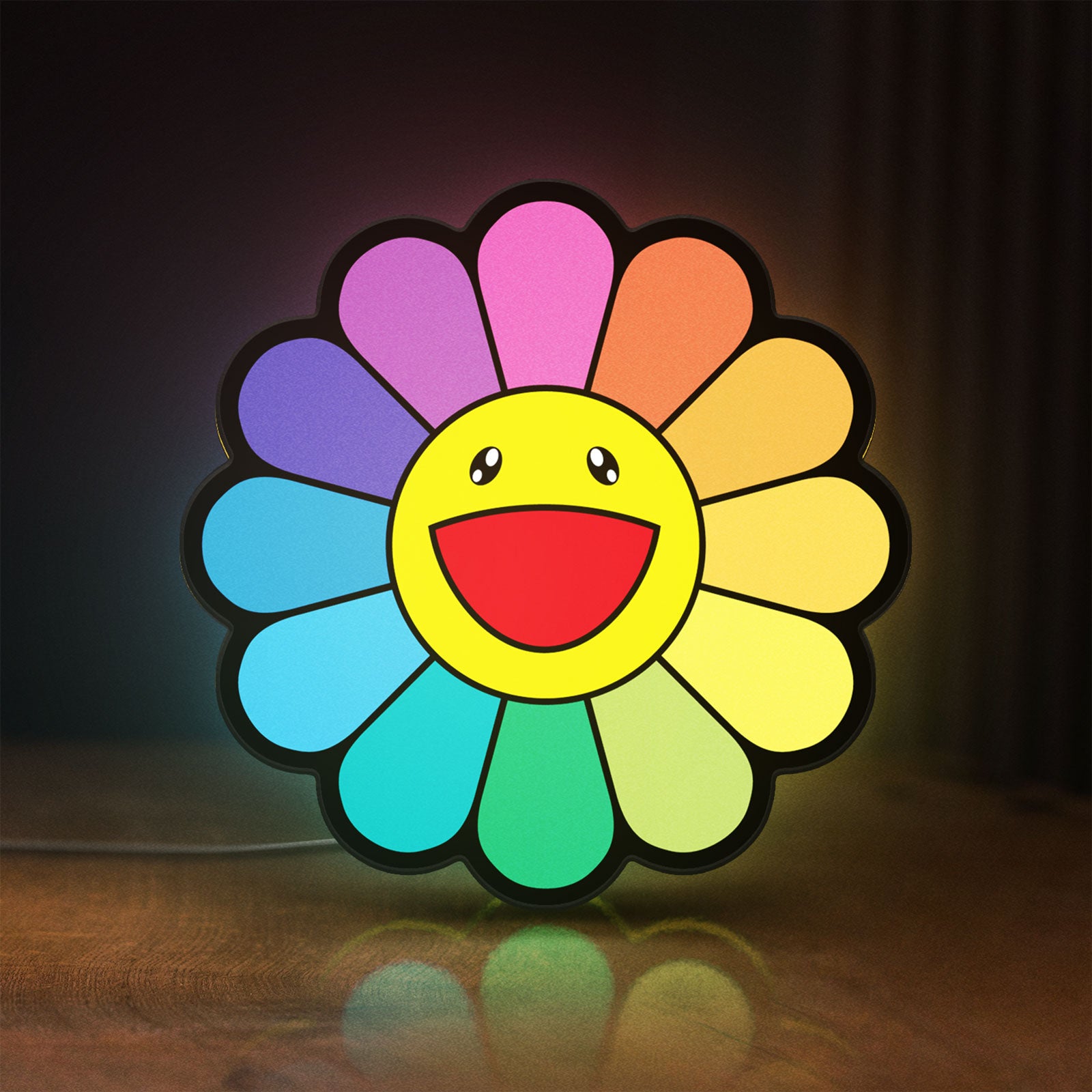 Front view of Takashi Murakami Rainbow Flower LED lightbox sign glowing on a wooden desk