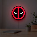 Deadpool LED lightbox hanging on a room wall with soft red light